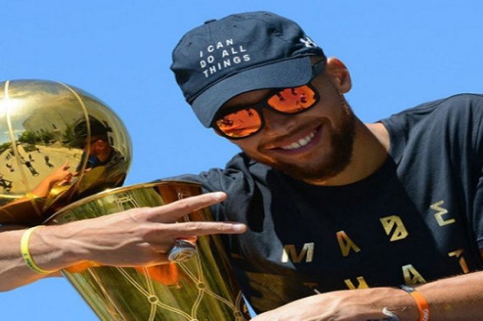 Stephen Curry berpose dengan membawa piala Larry O'Brien dalam sebuah acara perayaan juara NBA musim 2016/17.