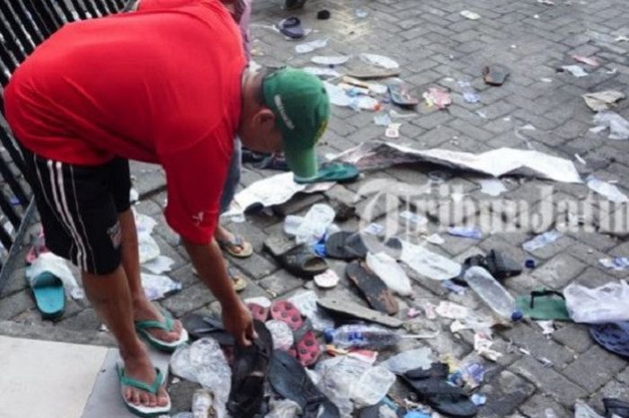 Seorang suporter mencari sandal layak pakai yang tak sengaja lepas dari pemiliknya saat antre panjang beli tiket laga semifinal Piala AFF U-19 2018, antara Indonesia vs Malaysia pada Kamis (12/7/2018).