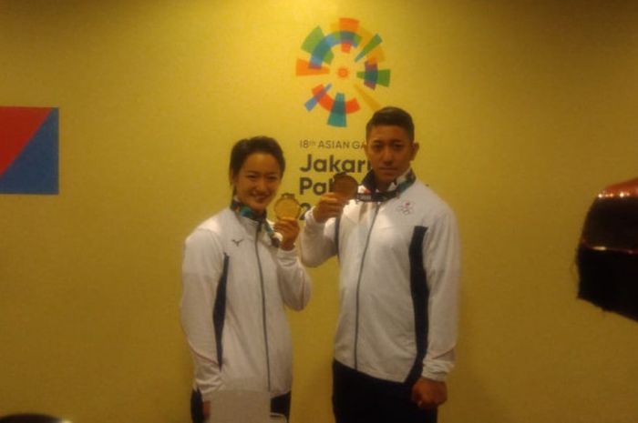 Karateka Jepang, Kiyou Shimizu (kiri) dan Ryo Kiyuna, berpose bersama setelah memenangi medali emas cabang karate nomor kata perorangan putra dan putri Asian Games 2018 di Plenary Hall Jakarta Convention Center, Sabtu (26/8/2018).