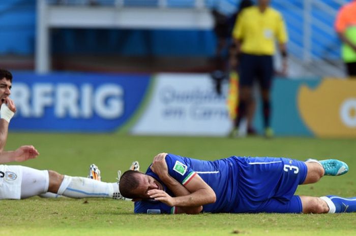 Penyerang Uruguay, Luis Suarez (kiri), memegang giginya usai menggigit bek Italia, Giorgio Chiellini, dalam laga Grup D Piala Dunia 2014 di Stadion Dunas Arena, Natal, Brasil pada 24 Juni 2014.