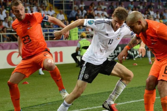 Penyerang timnas Jerman, Thomas Mueller (tengah), dijaga ketat dua pemain Belanda, Rafael van der Vaart (kiri) dan Nigel de Jong dalam partai Piala Eropa 2012 di Metalist Stadium, Kharkiv, 13 Juni 2012.