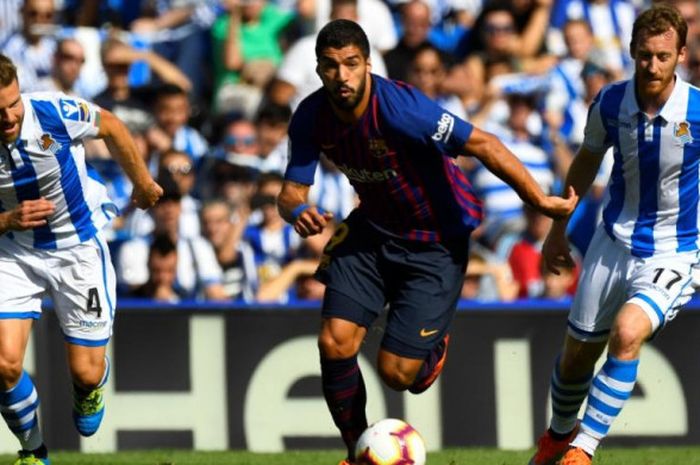 Luis Suarez (tengah) membawa bola di tengah kawalan pemain lawan dalam partai Liga Spanyol Real Sociedad kontra FC Barcelona di Stadion Anoeta, San Sebastian, 15 September 2018.