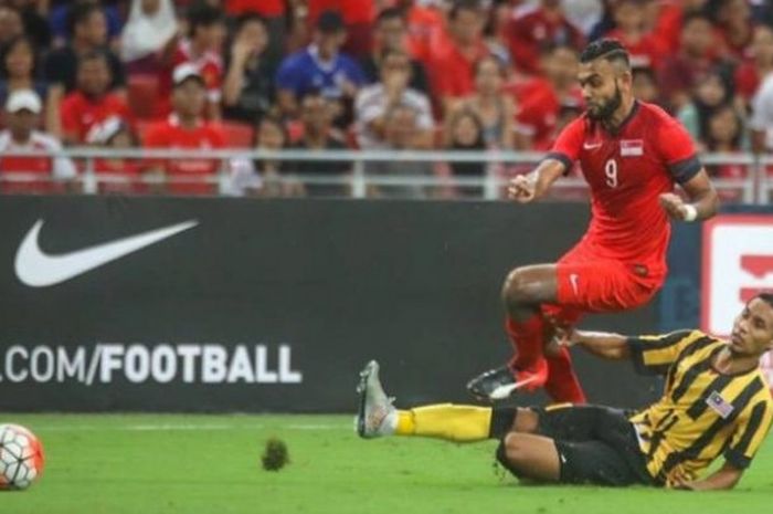 Gelandang Malaysia, Baddrol Bakhtiar (bawah) mencoba menghalangi laju pemain bertahan Singapura, Far