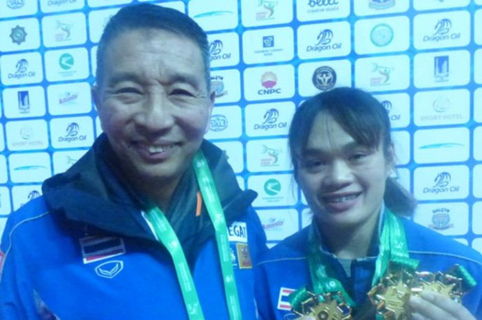 Lifter putri Thailand, Sukanya Srisurat, berpose dengan pelatihnya seusai meraih medali emas kelas 55 kg pada Kejuaraan Dunia Angkat Besi 2018 di Ashgabat, Turkmenistan.