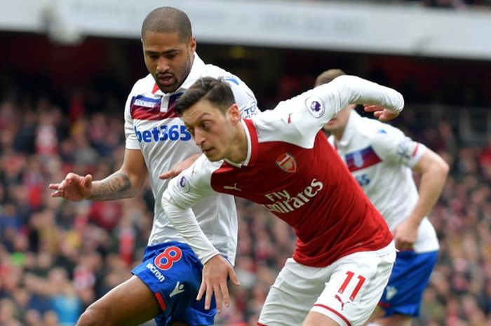 Gelandang Arsenal, Mesut Ozil, berduel dengan bek Stoke City, Glen Johnson, dalam laga Liga Inggris di Emirates Stadium, 1 April 2018.