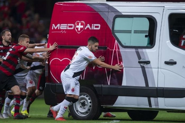 Pemain Flamengo Everton Ribeiro (kiri), Piris da Motta (tengah), bersama pemain Vasco da Gama Andrey (kanan) mendorong mobil ambulans mogok di tengah lapangan pertandingan yang membawa pemain cedera pada laga yang berlangsung di Stadion Mane Garrincha, Brasil, pada 16 September 2018.