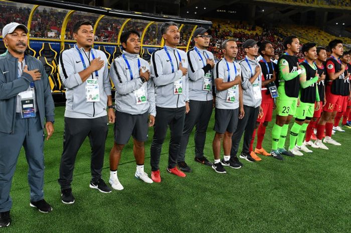     Pelatih Fakhri Husaini, staf pelatih Timnas U-16 Indonesia, dan para pemain cadangan menyanyikan lagu Indonesia Raya jelang laga versus Vietnam di Stadion Bukit Jalil, 24 September 2018.     