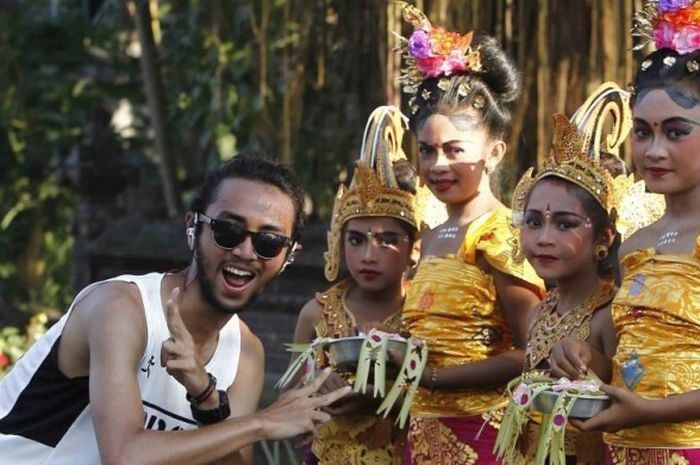 Seorang pelari nomor full-marathon berpose dengan beberapa penari cilik di ajang Maybank Bali Marathon 2016 di kawasan Gianyar, Bali, Minggu (28/8/2016).