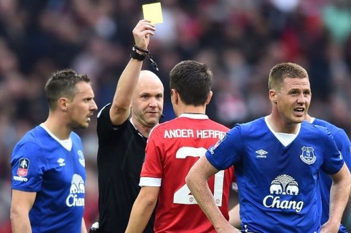 Gelandang Manchester United, Ander Herrera, mendapat kartu kuning dari wasit ANthony Taylor setelah menjatuhkan pemain Everton, Ross Barkley, di laga semifinal Piala FA, di WEmbley, 23 April 2016.