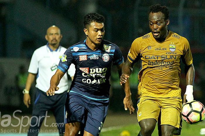 Gelandang Persib Bandung, Michael Essien (kanan), berupaya menguasai bola dibayangi pemain Arema FC, Junda Irawan, sementara pelatih caretaker Persib Bandung, Herrie Setyawan, mengawasi dari belakang saat kedua tim bertemu di laga pekan ke-19 Liga 1 di Stadion Kanjuruhan Malang, Jawa Timur, Sabtu (12/08/2017) malam.