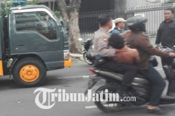 Seorang pria diamankan petugas saat ada demo Bonek dan pesilat PSHT di depan PN Surabaya, Kamis (1/3/2018). 