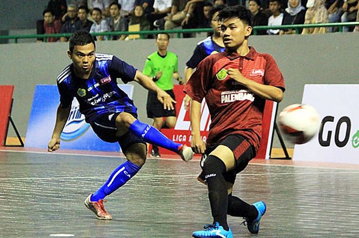 Pemain Politeknik Negeri Sriwijaya (kiri/kostum biru) menendang bola melewati pemain Universitas Muhammadiyah Palembang pada laga LIMA Futsal: Go-Jek Sumatra Conference 2018 di GOR Dempo, Jakabaring Sport City, Palembang, Rabu (17/10/2018).