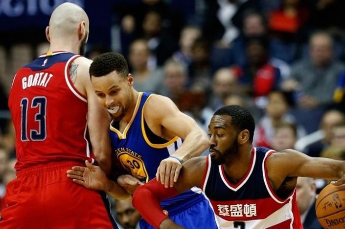 Pemain Golden State Warriors Stephen Curry (tengah), sedang berusaha melewati dua pemain Washington Wizards, Marcin Gortat (kiri) dan John Wall (kanan) pada lanjutan kompetisi NBA musim 2015-2016 di Verizon Center, Rabu (3/2/2016) malam waktu setempat atau Kamis (4/2/2016) siang WIB.