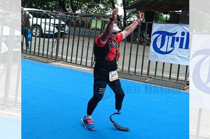 Pelari Singapura, Mohd Shariff Abdullah, mengangkat tangan saat sampai di garis finish Barelang Bridge Marathon 2016 di Batam, Minggu (11/12/2016) 