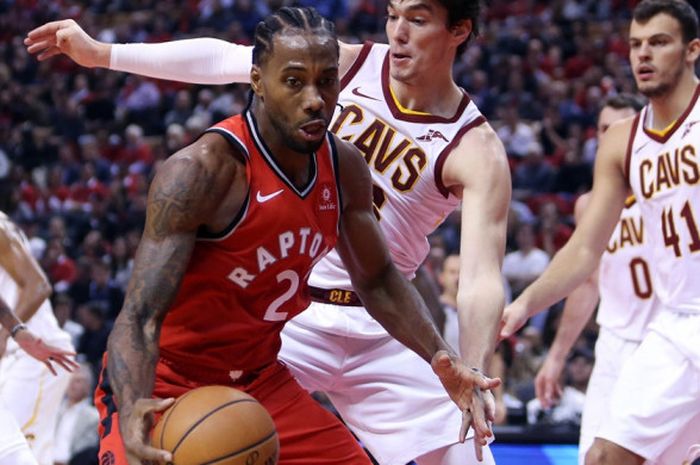 Forwad Toronto Raptors, Kawhi Leonard (jersey merah, #2), mendribel bola seraya dijaga pemain Cleveland Cavaliers, Cedi Osman, saat melakoni laga pembuka NBA 2018-2019 di Scotiabank Arena, Toronto, Kanada, Rabu (17/10/2018). Raptors menang 116-104 atas Cavaliers.