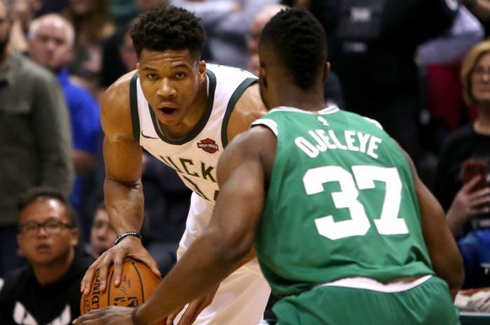 Pemain bintang Milwaukee Bucks, Giannis Antetokounmpo (jersey putih), mendribel bola seraya dikawal 