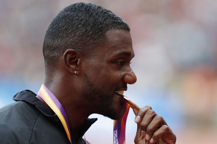 Sprinter Amerika Serikat, Justin Gatlin, menggigit medali emas yang dia raih setelah memenangi perlombaan nomor lari 100 meter Kejuaraan Dunia Atletik 2017, di Stadion London, Inggris, Minggu (6/8/2017).