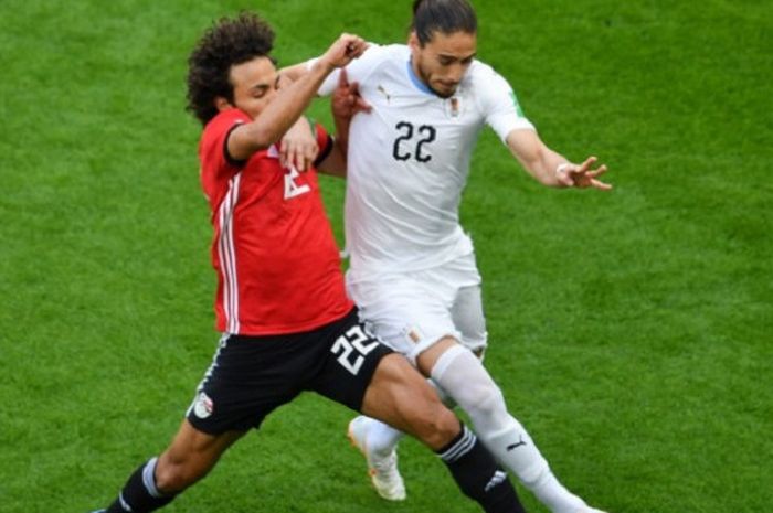 Amr Warda mencoba merebut bola yang dalam penguasaan Martin Caceres pada laga Mesir vs Uruguay di Yekaterinburg Arena, 15 Juni 2018.