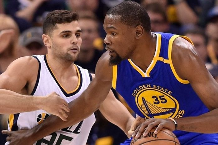 Forward Golden State Warriors, Kevin Durant (jersey biru, #33, berupaya melewati penjagaan pemain Utah Jazz, Raul Neto (#25), saat menjalani pertandingan gim ketiga babak semifinal play-off NBA Wilayah Barat di Vivint Smart Home Arena, Salt Lake City, Utah, Sabtu (6/5/2017) malam waktu setempat. Warriors menang dengan skor 102-91.