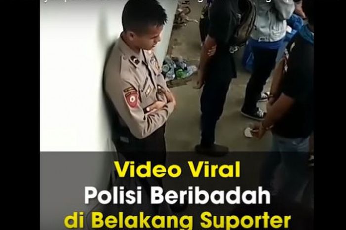 Seorang Polisi tampak melaksanakan ibadah sholat ketika tengah mengamankan Pertandingan Sepak Bola