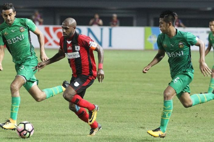 Kapten yang juga penyerang Persipura, Boaz Solossa diantara dua pilar Bhayangkara FC, Otavio Dutra dan I Putu Gede Juni Antara (kanan) pada laga lanjutan Liga 1 musim 2017 di Stadion Patriot, Kota Bekasi, Sabtu (9/9/2017) malam. 