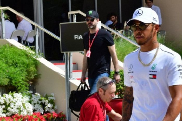 Pebalap Formula 1 dari tim Mercedes, Lewis Hamilton, berjalan di area paddock Sirkuit Internasional Bahrain, Sabtu (7/4/2018).