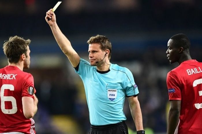 Wasit asal Jerman, Felix Brych (tengah), memberikan kartu kuning kepada gelandang Manchester United, Michael Carrick (kiri), yang disaksikan bek Manchester United, Eric Bailly, dalam pertandingan leg pertama babak perempat final Liga Europa melawan Anderlecht di Stadion Constant Vanden Stock, Brussels, 13 April 2017.