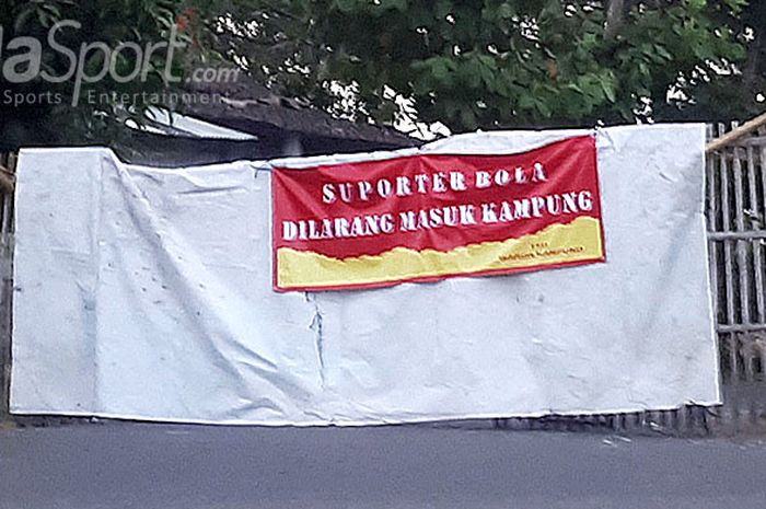 Warga sekitar Stadion Sultan Agung, Bantul, memasang spanduk larangan kepada suporter sepak bola agar tidak masuk kampung menjelang laga Persija Jakarta melawan Persebaya Surabaya pada laga lanjutan Liga 1 2018, Minggu (3/6/2018).