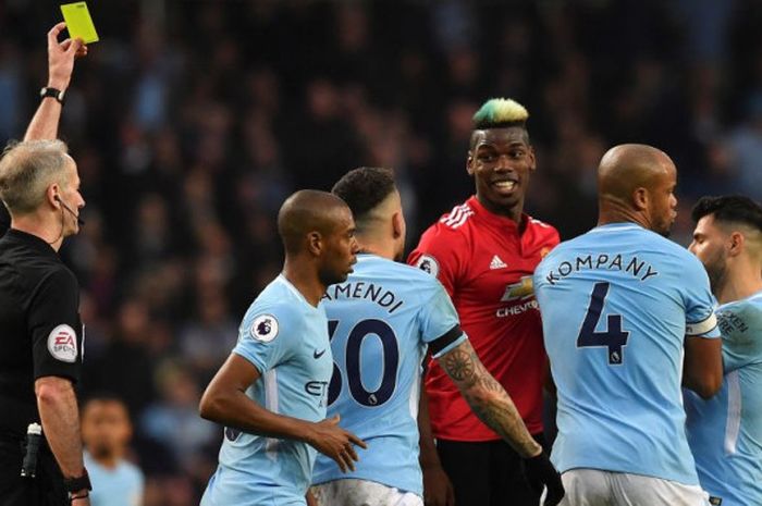 Gelandang Manchester United, Paul Pogba, menerima kartu kuning dari wasit Martin Atkinson pada laga Derbi Manchester di Stadion Etihad, Manchester, Sabtu (7/4/2018).