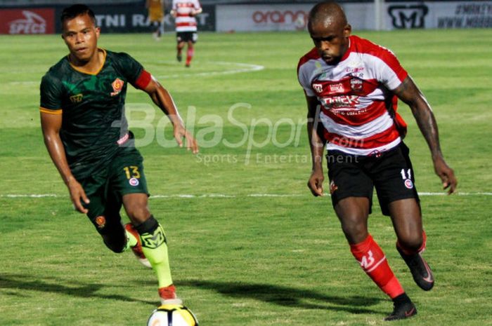 Penyerang Madura United, Greg Nwokolo (kanan), mencoba melewati hadangan pemain bertahan PS Tira, Manahati Lestusen, dalam laga pekan kedua Liga 1 2018 di Stadion Sultan Agung, Bantul, Senin (2/4/2018)