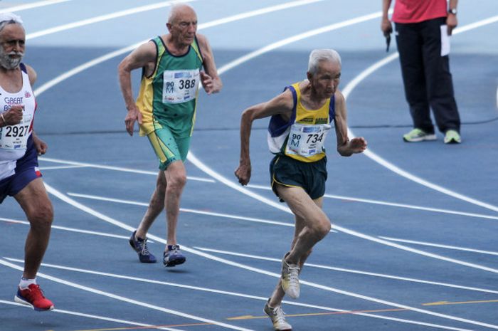 Sprinter usia 90 tahun ke atas, Yoshiyuki Shimizu (Brazil/seragam kuning paling depan), Falbir Singh Deol (Inggris/Seragam putih posisi kedua), dan Rad Leovic (Australia/seragam hijau posisi ketiga), tengah bersaing di nomor lari 100 meter Kejuaraan Dunia Masters Atletik 2018.