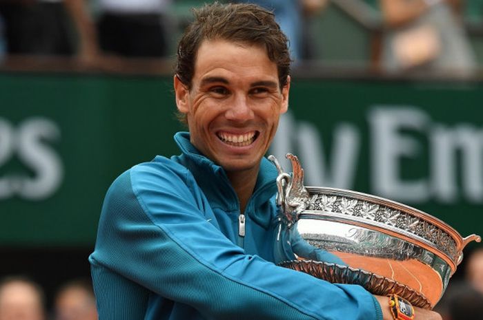 Petenis tunggal putra Spanyol, Rafael Nadal, memeluk La Coupe des Mousquetaires yang dia raih setelah menjuarai turnamen Roland Garros 2018 di Paris, Prancis, Minggu (10/6/2018).