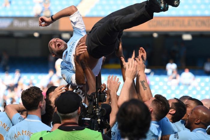 Pemain Manchester City mengangkat Pep Guardiola ke udara saat melakukan selebrasi memenangi gelar Liga Inggris musim 2017-2018 di Stadion Etihad, Minggu (6/5/2018) malam WIB.