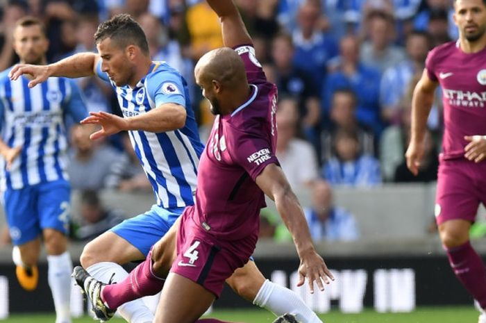 Vincent Kompany (4) melancarkan tekel kepada Tomer Hemed saat Manchester City melawan Brighton and Hove Albion pada partai Liga Inggris di Stadion Amex, Sabtu (12/8/2017).