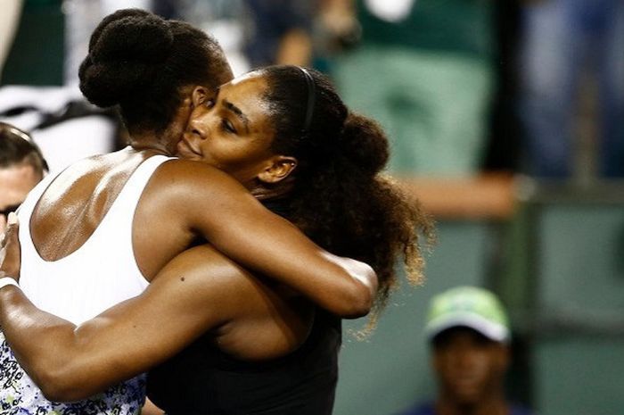 Venus Williams (baju putih) dan Serena Williams (baju hitam) saat berpelukan usai keduanya bertemu p