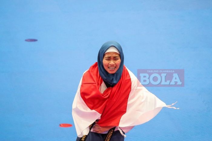 Atlet taekwondo, Defia Rosmaniar, merayakan keberhasilan meraih medali emas pada nomor poomsae individu putri di Plenary Hall JCC, Jakarta, Minggu (19/8/2018).