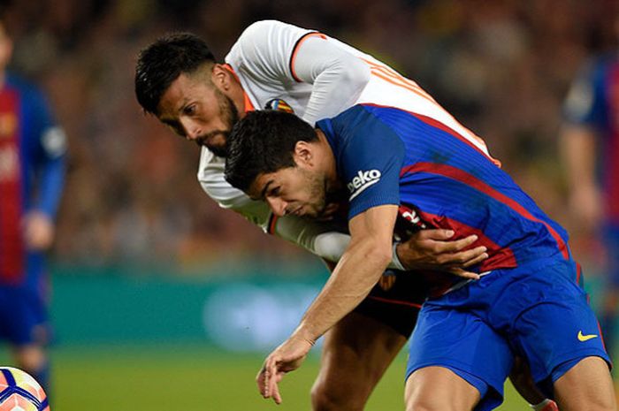 Bek Valencia, Ezequiel Garay, berebut bola dengan penyerang Barcelona, Luis Suarez, dalam laga lanjutan Liga Spanyol 2017-2018 di Stadion Camp Nou, Barcelona, pada 19 Maret 2017.