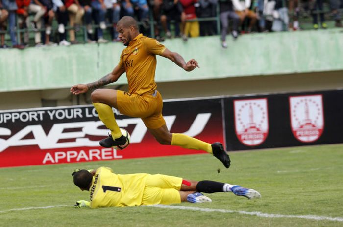 Striker Bhayangkara FC, David da Silva melompat di atas kiper Persis, Galih Sudaryono pada uji coba di Stadion Manahan, Solo, Minggu (25/2/2018) sore.