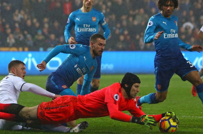 Aksi kiper Arsenal, Petr Cech (merah), saat mengamankan bola dari andaman bek Swansea City, Alfie Mawson, dalam laga Liga Inggris 2017-2018 di Stadion Liberty, Swansea, Wales, pada Selasa (30/1/2018).