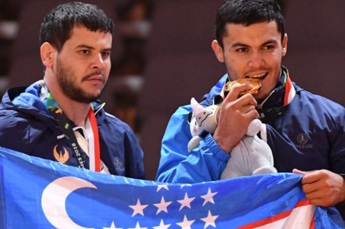 Dua atlet kurash Uzbekistan peraih medali emas Shermukhmamad Jandreev (kanan) dan Yakhyo Imamov (kiri) berfoto bersama usai mengikuti upacara penyerahan medali kelas putra -90kg Asian Games 2018 di Assembly Hall JCC Senayan, Jakarta, Kamis (30/8/2018)