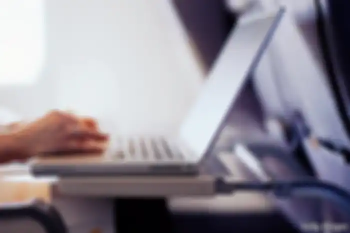 Woman typing on laptop computer in commercial airplane