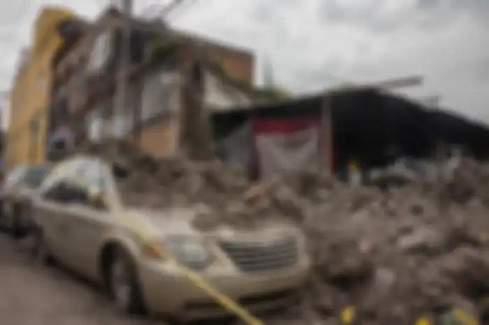 Sebuah gedung hancur dan reruntuhannya menimpa mobil saat gempa di Mexico 