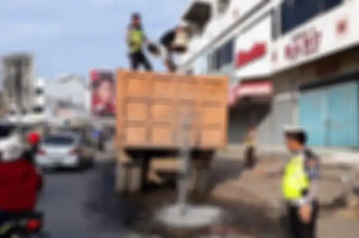Petugas Satuan Lalu Lintas (Satlantas) Polres Tanggamus berinisiatif menimbun lubang Jalan Lintas Barat (Jalinbar) di depan Pasar Induk Pringsewu, Jumat (11/1)&nbsp;