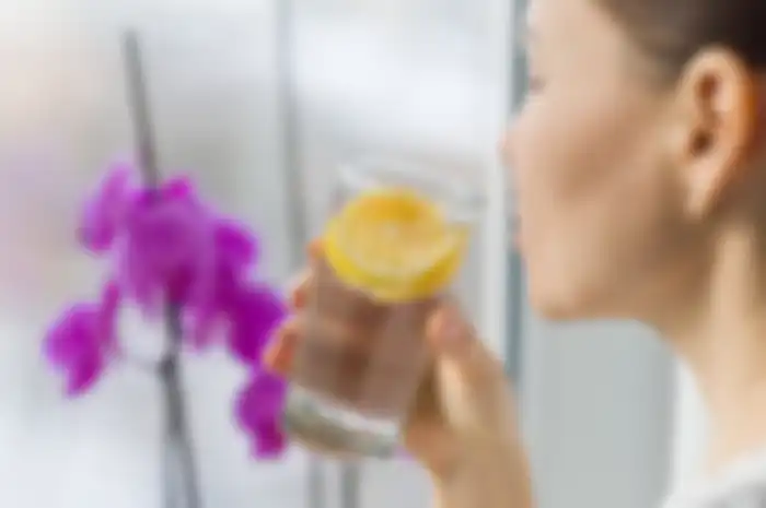 Woman drinking summer refreshing fruit flavored infused water with fresh organic lemon. Healthy eating, diet concept.