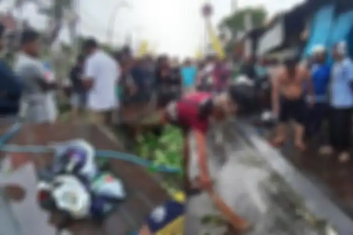Warga membersihkan lokasi tempat pemotor asal Pasuruan tewas tertimpa pohon di Jalan Tukad Pakerisan, Kelurahan Panjer, Renon, Denpasar, Bali, Kamis sore (24/1/2019). (Inzert) Pecahan helm yang digunakan korban.&nbsp;
