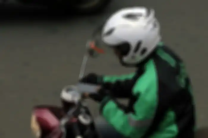 Ojek online sedang melihat GPS pada HP-nya