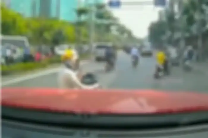 Seorang wanita menerima telepon di tengah jalan raya
