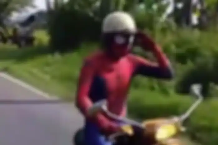 Pemotor berkostum Spiderman menunggangi Vespa PTS kuning