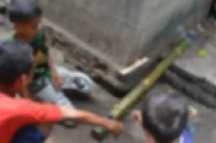 Tiga orang anak sekolah dasar di Kompleks Mabako, Kelurahan Watunggene, Kecamatan Kota Komba, Manggarai Timur, Flores, NTT, Jumat (19/12/2014) membunyikan meriam bambu di samping rumah mereka. Tradisi meriam bambu merupakan warisan leluhur orang Flores untuk menyambut kelahiran Isa Almasih.