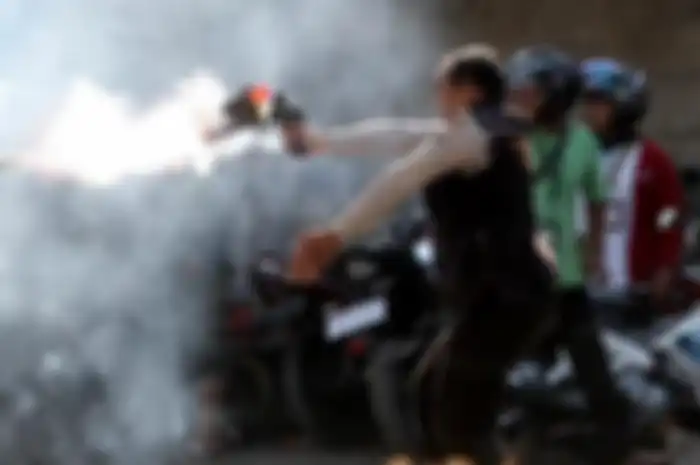 Polisi sedang melontarkan gas air mata.